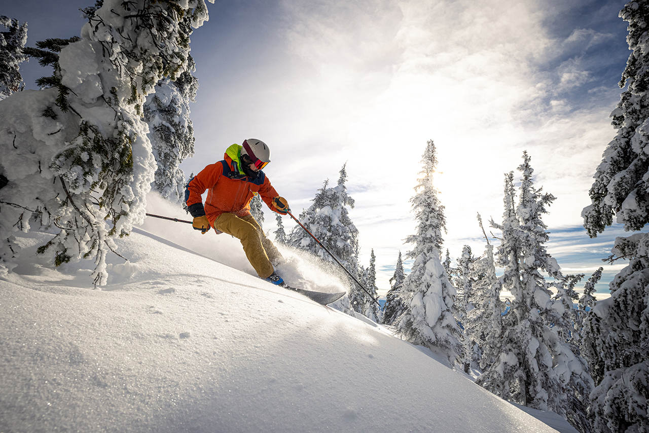 Manskiing.jpg skiing down a snowy slope with trees