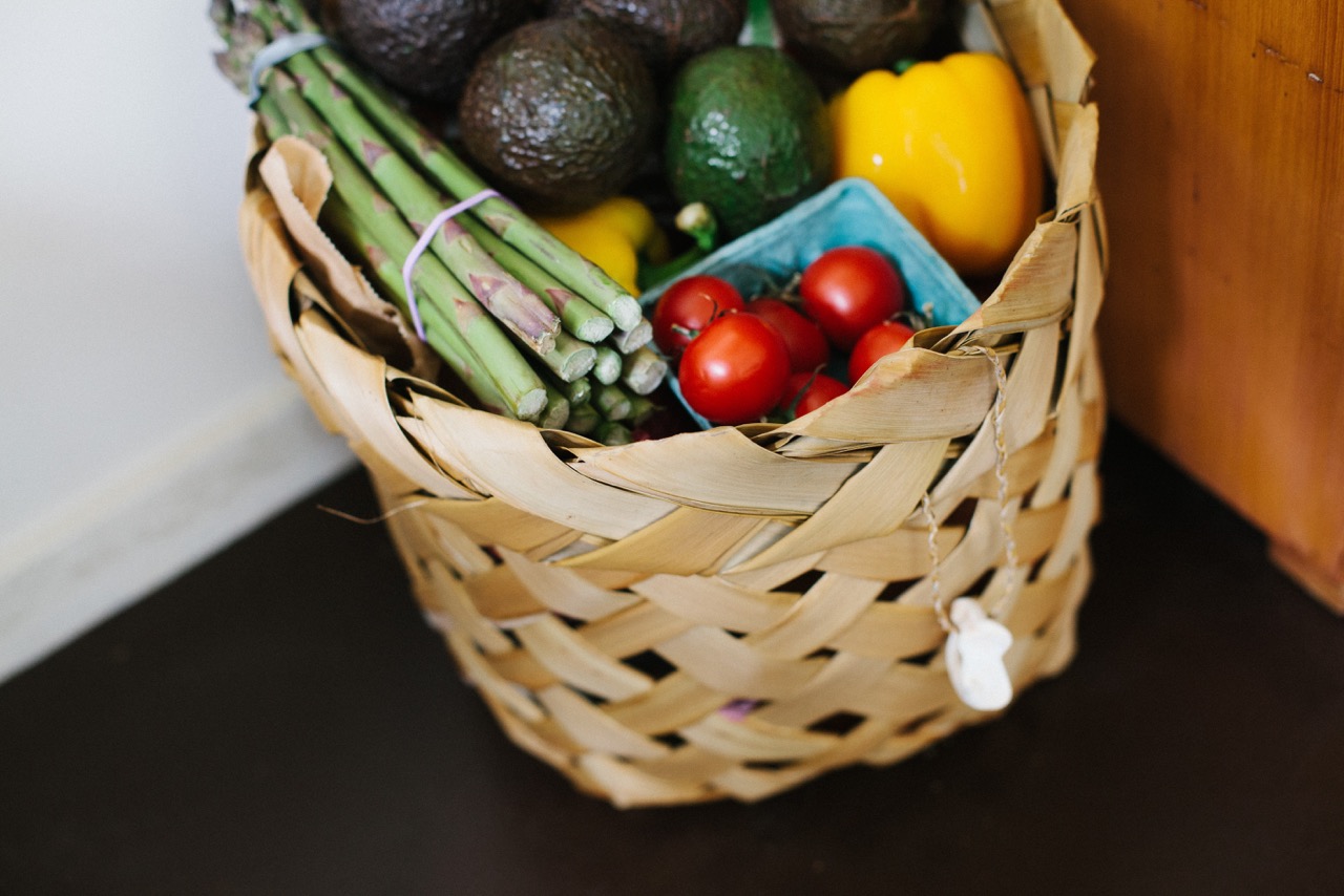 Woven basket with vegetables including tomatoes asparagus and bell pepper