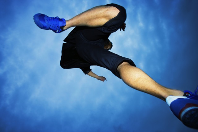 Low-angle view of a person jumping, wearing blue shoes